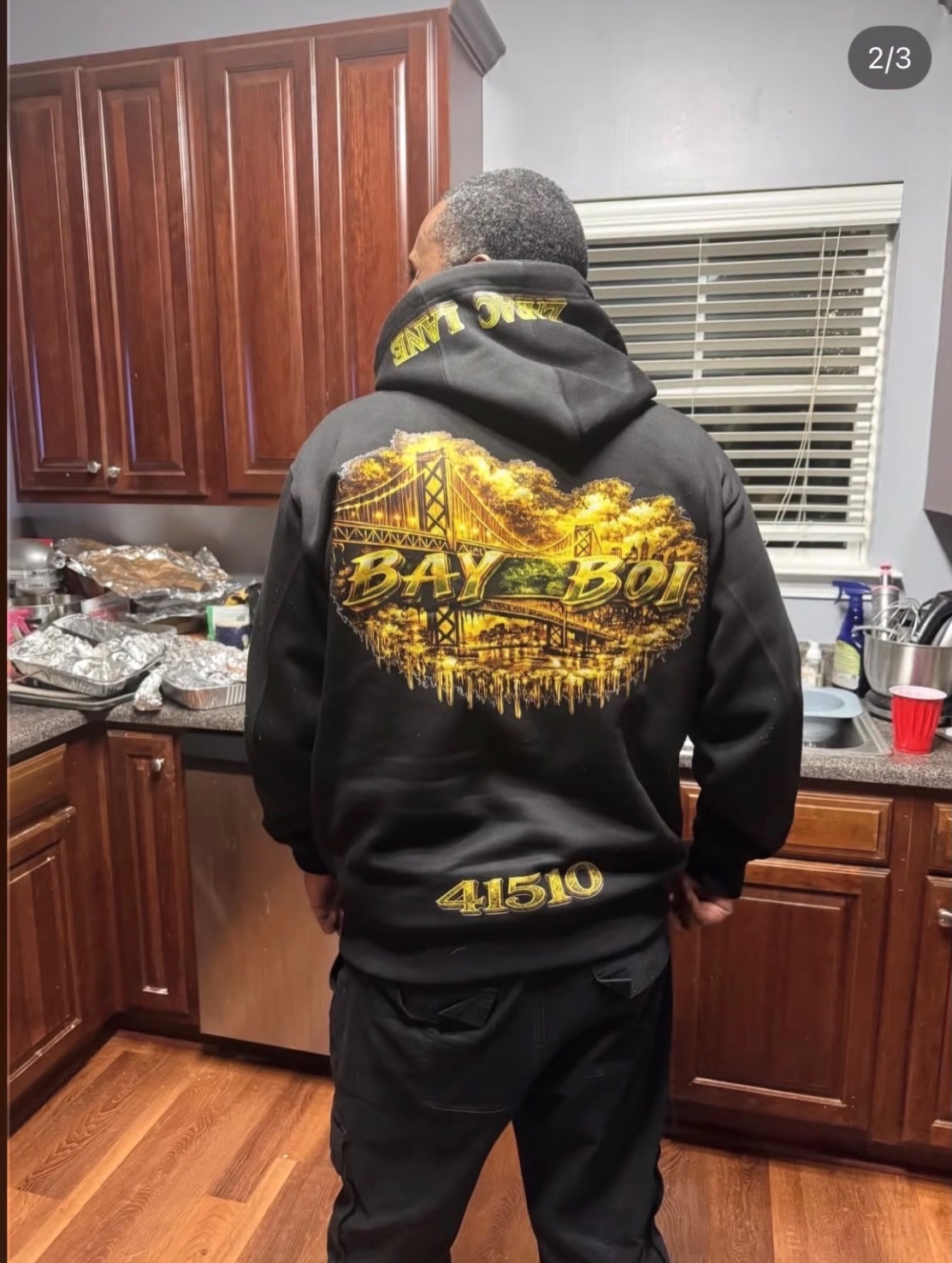 Back view of a black hoodie with a gold BAY BOI bridge graphic